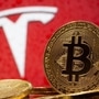 Representations of virtual currency Bitcoin are seen in front of Tesla logo. (REUTERS)