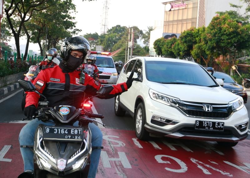 Volunteer bikers navigating traffic in Jakarta.