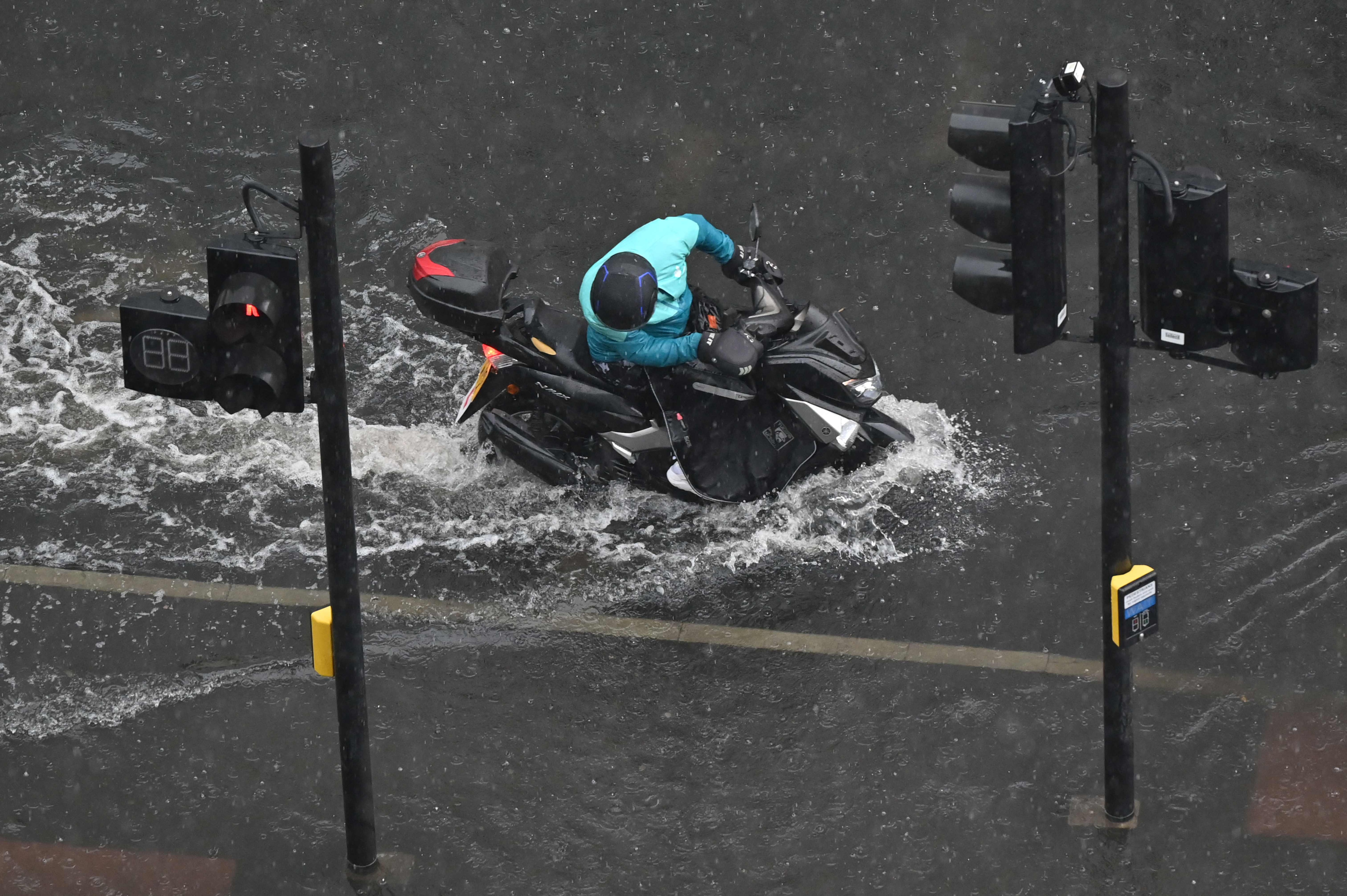 A motorcyclist tries to ride through deep water on a flooded road in The Nine Elms district of London.