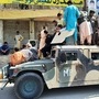 Taliban fighters and local residents sit over an Afghan National Army (ANA) humvee vehicle along the roadside in Laghman province. (AFP)