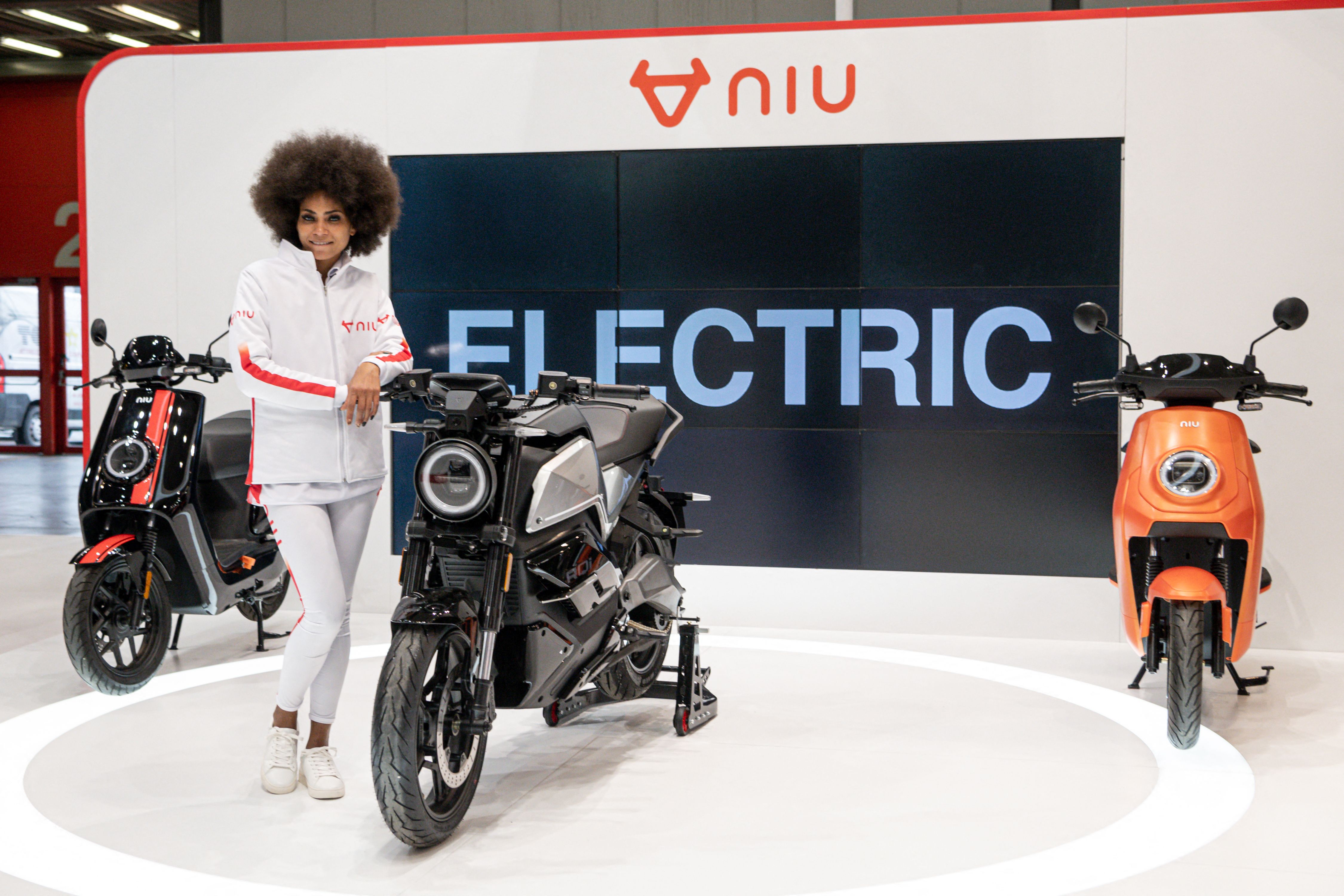 A model poses by motorcycles and motorbikes on display on the NIU stand at EICMA. (AFP)