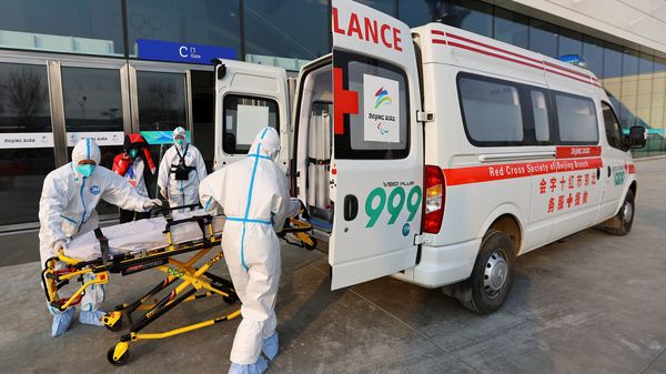 Red cross ambulance staff wearing protective suits to protect from the coronavirus disease load a stretcher into an ambulance, outside the main press centre ahead of the Beijing 2022 Winter Olympics. (REUTERS)