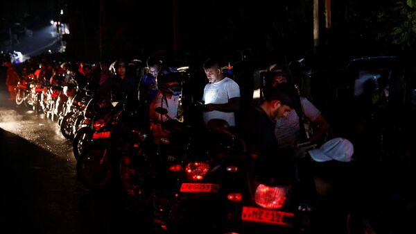 People stand next to their motorbikes as they queue to buy petrol during the early hours of the morning at a fuel station on the outskirts of Colombo.