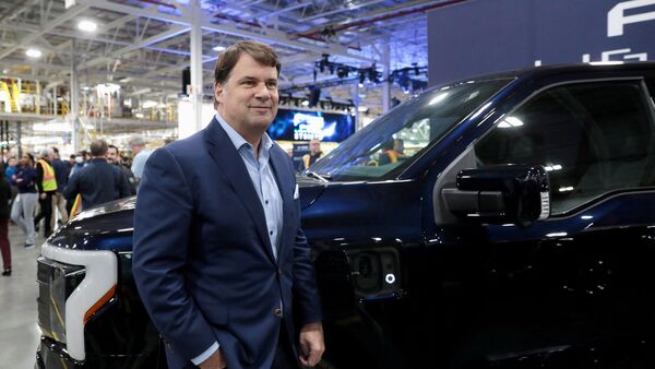 File photo of Ford CEO Jim Farley posing next to a model of F-150 Lightning electric pickup truck. (REUTERS)