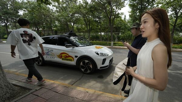 Workers prepare to catch a ride with a self-driving taxi developed by tech giant Baidu Inc. (AP)