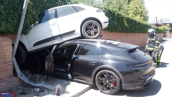 The Porsche Taycan and the Porsche Macan crash through a brick wall. (Image: Twitter/112 Comunidad de Madrid)