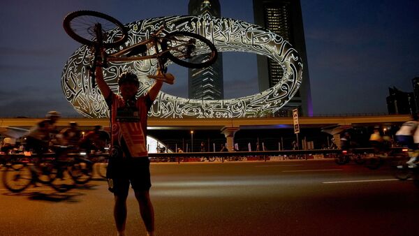 A bicyclist poses for a photograph in front of the Museum of the Future and Emirates Towers, in Dubai, United Arab Emirates A bicyclist poses for a photograph in front of the Museum of the Future and Emirates Towers, in Dubai, United Arab Emirates