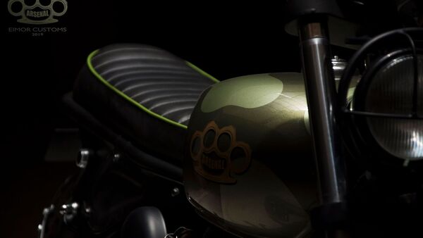 The motorcycle retains its fuel tank but now gets custom camo green paint scheme with Arsenal written on it. The motorcycle retains its fuel tank but now gets custom camo green paint scheme with Arsenal written on it.