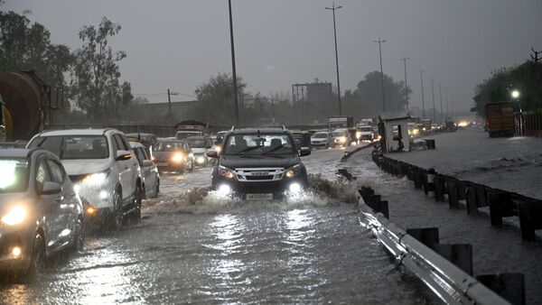Vehicles wade through a waterlogged stretch in heavy rain on the NH-48 service road near Narsinghpur village, in Gurugram.