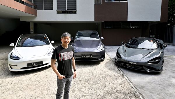 Eu Gene Goh poses for a photo with his three cars, a Tesla Model 3, a Tesla Model Y and a McLaren 765LT, in Singapore on March 11, 2023.  (Reuters)