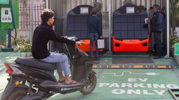 A man sits on his electric scooter as he waits for a battery change at a Sun Mobility battery change station in New Delhi.  (Picture) (REUTERS)