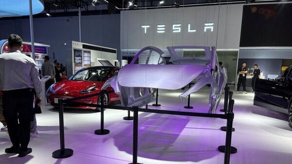 A man stands next to a Tesla Model 3 electric car at the third China International Consumer Goods Fair in Haikou, China.  (Reuters)