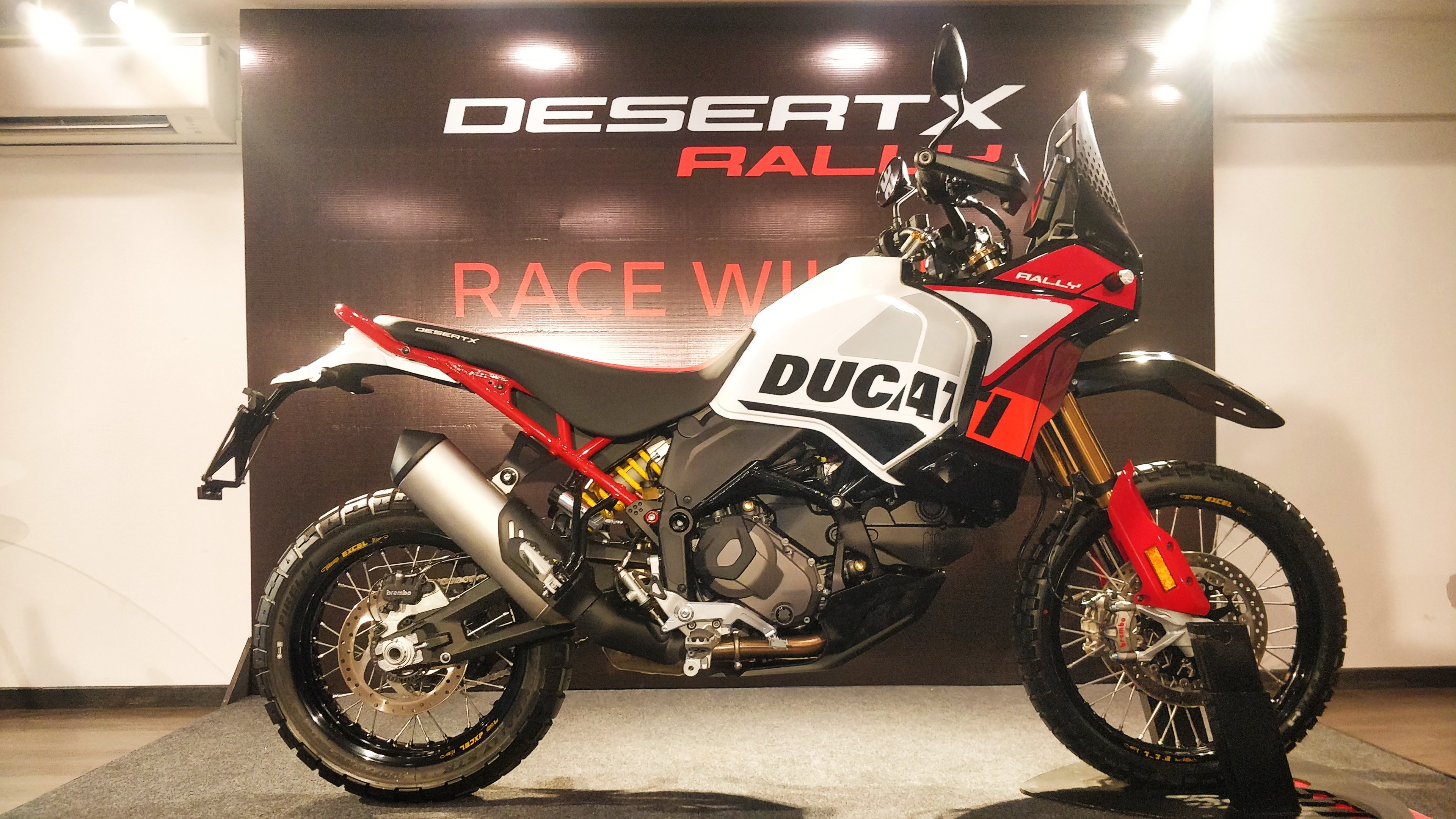 The Ducati DesertX Rally gets a higher-mounted front mudguard, new Takasago Excel wire-spoked wheels, a carbon sump guard, and a new livery Ducati DesertX Rally Delivery