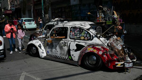 People walk past an antique Volkswagen Beetle, known in Mexico as a Vocho, before a parade a day after World Vocho Day in Mexico City on Sunday (June 23, 2024). Volkswagen Beetle Mexico