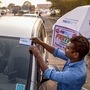 Navi Mumbai: A worker fixes a FASTag sticker on the windscreen of a car, at Vashi Toll Plaza on Sion Panvel Highway, Mumbai, Friday, Nov. 29, 2019. From Dec. 1, making toll payments via FASTag will become mandatory at national as well as state highways. (PTI Photo)(PTI11_29_2019_000194B) (PTI)