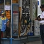 A traffic police personnel and a fuel attendant stand near a notice announcing the ban on refuelling petrol cars older than 15 years and diesel vehicles older than 10 years, displayed at a gas station in New Delhi on July 1, 2025. (AFP)