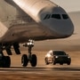 The Porsche Cayenne Turbo Electric prototype drives beneath Stratolaunch's Roc aircraft during a precision take-off test at Mojave Air and Space Port.