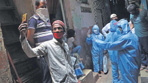 A man takes a selfie as health workers collect details of residents in the virus-hit slum of Dharavi in Mumbai on Monday.ap (MINT_PRINT) A man takes a selfie as health workers collect details of residents in the virus-hit slum of Dharavi in Mumbai on Monday.ap (MINT_PRINT)
