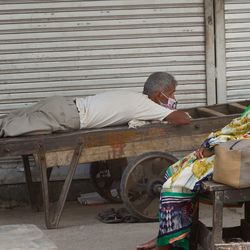 দিল্লিতে বন্ধ দোকানের বাইরে বিশ্রাম নিচ্ছেন দু'জন (ছবি সৌজন্য পিটিআই)
