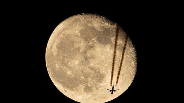 TOPSHOT - An aircraft flies above Iraq's southern city of Basra past the waning gibbous moon late on April 18, 2022. (Photo by Hussein Faleh / AFP) (AFP)