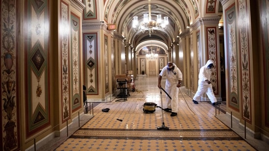Workers clean damage near an overrun Capitol Police checkpoint a day after a pro-Trump mob broke into the US Capitol on January 7.(Brendan Smialowski / AFP)