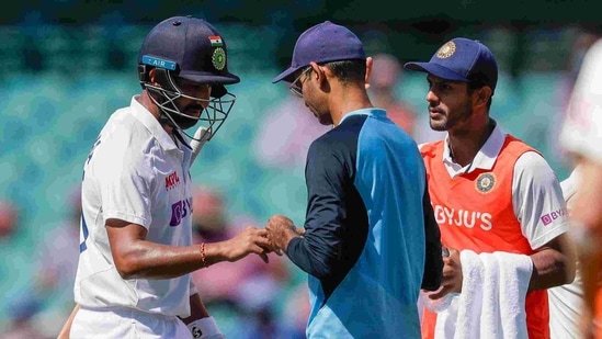 India's Cheteshwar Pujara, left, has treatment to a finger injury during play on day three of the third cricket test between India and Australia at the Sydney Cricket Ground, Sydney, Australia, Saturday, Jan. 9, 2021.(AP)