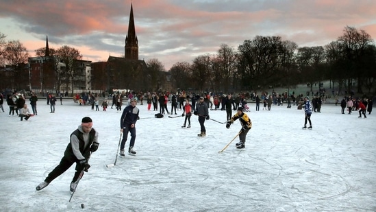 People playing ice hockey as the sun sets on a frozen pond in Queen's Park, Glasgow, Scotland on January 3.(Andrew Milligan/PA via AP)