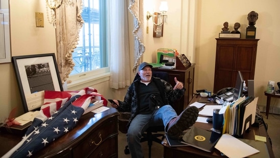 A supporter of US President Donald Trump sits inside the office of US Speaker of the House Nancy Pelosi as he protest inside the US Capitol in Washington, (AFP)