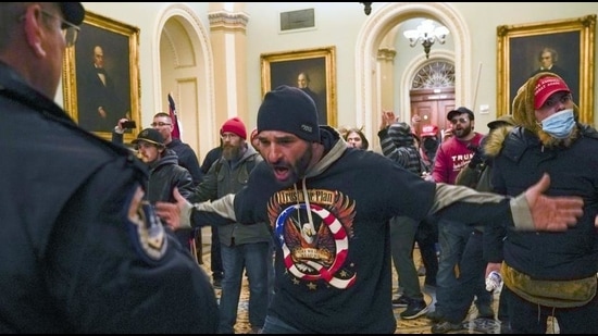 Trump supporters gesture to US Capitol Police in the hallway outside of the Senate chamber after breaching the halls of the Capitol in Washington, January 6, 2021 (AP)