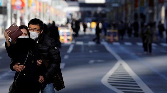 A man and woman wearing protective masks, amid the coronavirus disease (COVID-19) outbreak, take their selfie at Ginza shopping district which closed to cars on Sunday in Tokyo, Japan, January 10, 2021. REUTERS/Kim Kyung-Hoon (REUTERS)