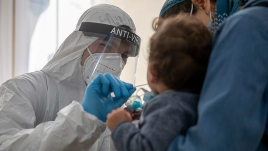 An Israeli health care professional tests a woman and her child for the coronavirus at a testing centre in Jerusalem. (AP) An Israeli health care professional tests a woman and her child for the coronavirus at a testing centre in Jerusalem. (AP)