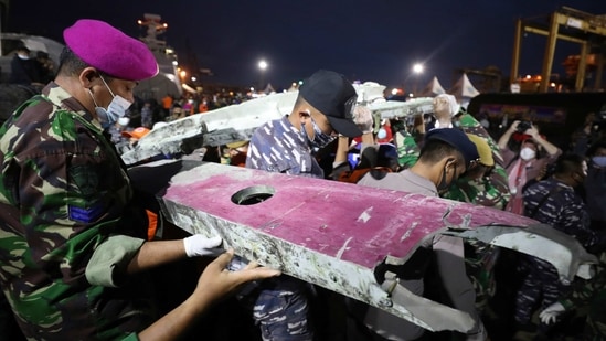 Soldiers and rescue personnel carry debris found in the waters off Java Island around where a Sriwijaya Air passenger jet crashed on Saturday, (AP)