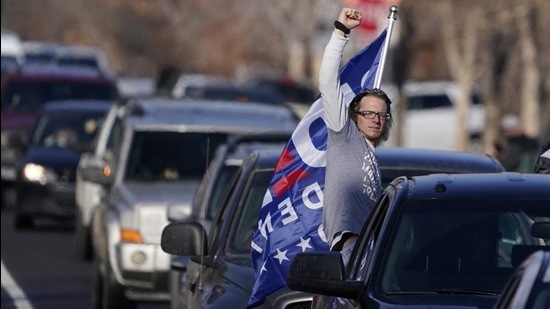 A man raises his arm while riding in the bed of a pickup truck during a gathering calling for the impeachment of President Donald Trump at South High School before a car rally through the streets of downtown Sunday, January 10, 2021, in Denver, US. (AP) A man raises his arm while riding in the bed of a pickup truck during a gathering calling for the impeachment of President Donald Trump at South High School before a car rally through the streets of downtown Sunday, January 10, 2021, in Denver, US. (AP)