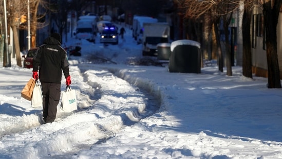 A person holding bags walks through a snow-covered street after heavy snowfall in Madrid on January 11. The Spanish government has insisted the travel chaos will not affect the distribution of the coronavirus vaccine, with 350,000 doses due to be rolled out nationwide on January 11.(Sergio Perez / REUTERS)