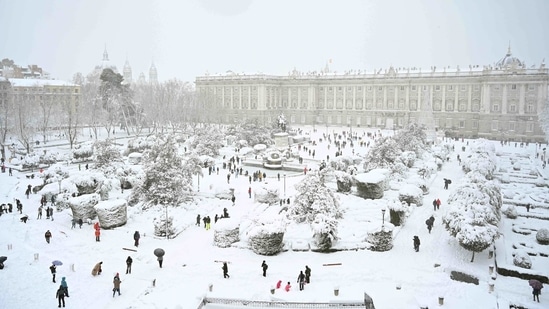 People out in the snow outside the Royal Palace in Madrid on January 9. In Madrid, authorities are calling on citizens to avoid using the few lanes that civil protection and military battalions, aided by snowplows and bulldozers, have managed to clear for ambulances and emergency vehicles.(Gabriel Bouys / AFP)
