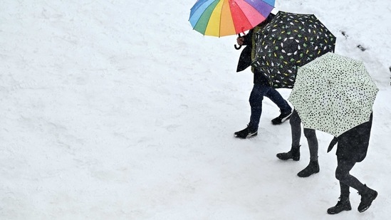 People holding umbrellas walk amid a heavy snowfall in Madrid on January 9. The underground train system has become the only viable way for people to commute to work. Lacking enough salt and snowploughs, officials had as on January 11 only managed to clear main roads of snow and fallen tree branches, with most pavements, smaller roads and residential areas still covered.(Gabriel Bouys / AFP)