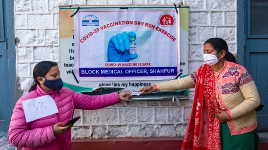 A health official asks for an ID from a volunteer during a mock vaccination drill in Dharamshala on January 11. More than 61,000 programme managers, 200,000 vaccinators and 370,000 other vaccination team members have been trained for the drive so far at state, district and block levels, according to the health ministry.(Ashwini Bhatia / AP)