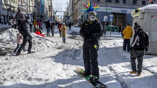 A man snowboards down the Gran Via avenue in downtown Madrid on January 10. Much of the city's main services remained closed on January 11, including the main wholesale market, although some supermarkets and newsstands opened for the first time in three days.(Manu Fernandez / AP)