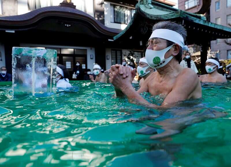 Participants wearing protective face masks amid the coronavirus disease (COVID-19) outbreak, pray as they take an ice-cold bath during a ceremony to purify their souls and to wish for overcoming the pandemic at the Teppozu Inari shrine in Tokyo, Japan. (REUTERS)