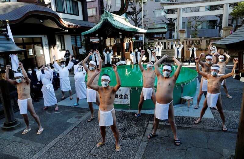 Participants wearing protective face masks amid the coronavirus disease (COVID-19) outbreak, warm up before taking an ice-cold bath during a ceremony to purify their souls and to wish for overcoming the pandemic at the Teppozu Inari shrine in Tokyo, Japan. (REUTERS)