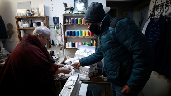 Jaime Walfre Aguilar Martinez picks out a tag to have sewn onto the stuffed bear that Erendira Guerrero will make for him from his father's favorite sweater, hanging right, in Guerrero's home workshop on January 11. Guerrero charges about $30 for a bear and attaches notes that sometimes read, “This is a shirt I used to wear, whenever you hold it know that I am there. Love, Dad.” (Christian Chavez / AP) Jaime Walfre Aguilar Martinez picks out a tag to have sewn onto the stuffed bear that Erendira Guerrero will make for him from his father's favorite sweater, hanging right, in Guerrero's home workshop on January 11. Guerrero charges about $30 for a bear and attaches notes that sometimes read, “This is a shirt I used to wear, whenever you hold it know that I am there. Love, Dad.” (Christian Chavez / AP)
