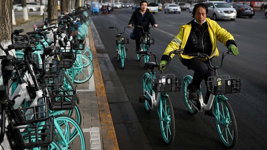 Men guide bicycles while riding along a street in Beijing on January 13. Most of the new cases were reported near Beijing, but a province in the far northeast also saw a rise in infections, Reuters reported.(Wang Zhao / AFP)