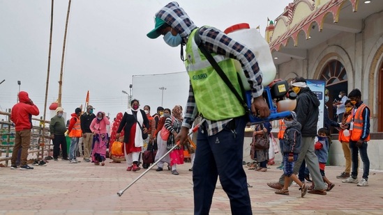 A man wearing a protective mask sprays disinfectant as a preventive measure against the coronavirus disease (Covid-19) as pilgrims arrive at the confluence of the river Ganges and the Bay of Bengal ahead of "Makar Sankranti" festival, at Sagar Island in the eastern state of West Bengal, India.