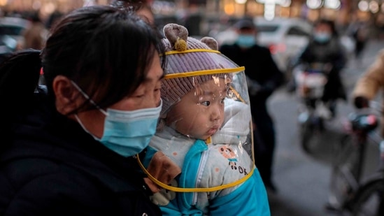 A woman holds a child outside a shopping mall complex in Wuhan on January 13. While Wuhan was the initial epicentre of the novel coronavirus, which emerged there in late 2019, China had in recent months largely kept it at bay.(Nicolas Asfouri / AFP)