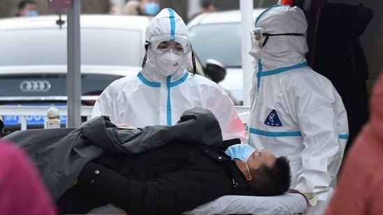 Medical workers wearing protective suits escort a patient to the fever clinic at a hospital in Beijing on January 13. The National Health Commission on January 13 reported a total of 115 new confirmed cases on the mainland, compared with 55 the previous day, the highest daily increase since July 30, Reuters reported.(Greg Baker / AFP)