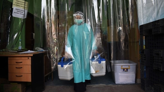 TOPSHOT - A health worker delivers containers of Covid-19 vaccines produced by China's Sinovac, from a cold room in Bandung on January 13, 2021, as the sprawling archipelago of nearly 270 million kicks off a mass innoculation drive in a bid to control soaring case rates. (Photo by Timur Matahari / AFP) (AFP) TOPSHOT - A health worker delivers containers of Covid-19 vaccines produced by China's Sinovac, from a cold room in Bandung on January 13, 2021, as the sprawling archipelago of nearly 270 million kicks off a mass innoculation drive in a bid to control soaring case rates. (Photo by Timur Matahari / AFP) (AFP)