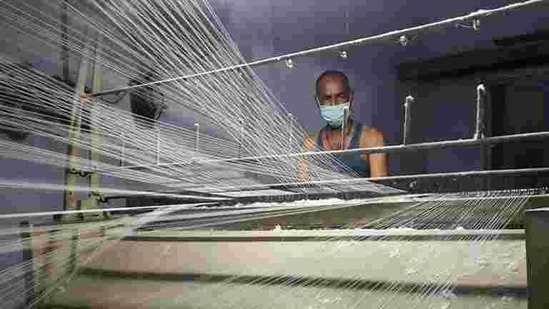 A worker wearing a protective face mask works on a loom in a textile factory, amidst the coronavirus disease (Covid-19) outbreak, in Meerut, India.(REUTERS) A worker wearing a protective face mask works on a loom in a textile factory, amidst the coronavirus disease (Covid-19) outbreak, in Meerut, India.(REUTERS)