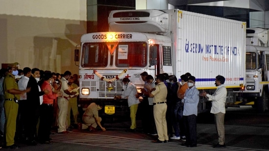 A police officer performs prayers in front of a truck carrying the first consignment of COVISHIELD, a coronavirus disease vaccine developed by AstraZeneca and Oxford University, before it leaves the Serum Bio-Pharma Park of Serum Institute of India in Pune on January 12. India is scheduled to begin its vaccination drive on January 16, which is set to be the largest globally.(Kalpesh Nukte / AP)
