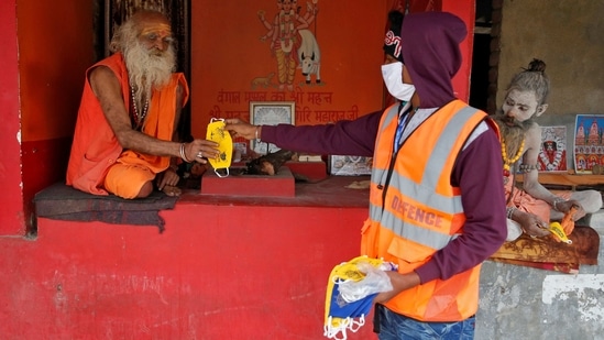 A man distributes face masks amongst sadhus ahead of Makar Sankranti festival at Sagar Island on January 13. Continuing with the trend of more daily recoveries from the disease than new cases, 17,652 more patients recovered in the last 24 hours, taking the total number of recovered cases to 10,146,763, the ministry’s dashboard showed.(Rupak De Chowdhuri / REUTERS)