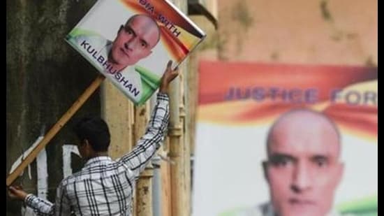 In this file photo taken on July 17, 2019, an Indian man holds a placard depicting Kulbhushan Jadhav. (AFP file)